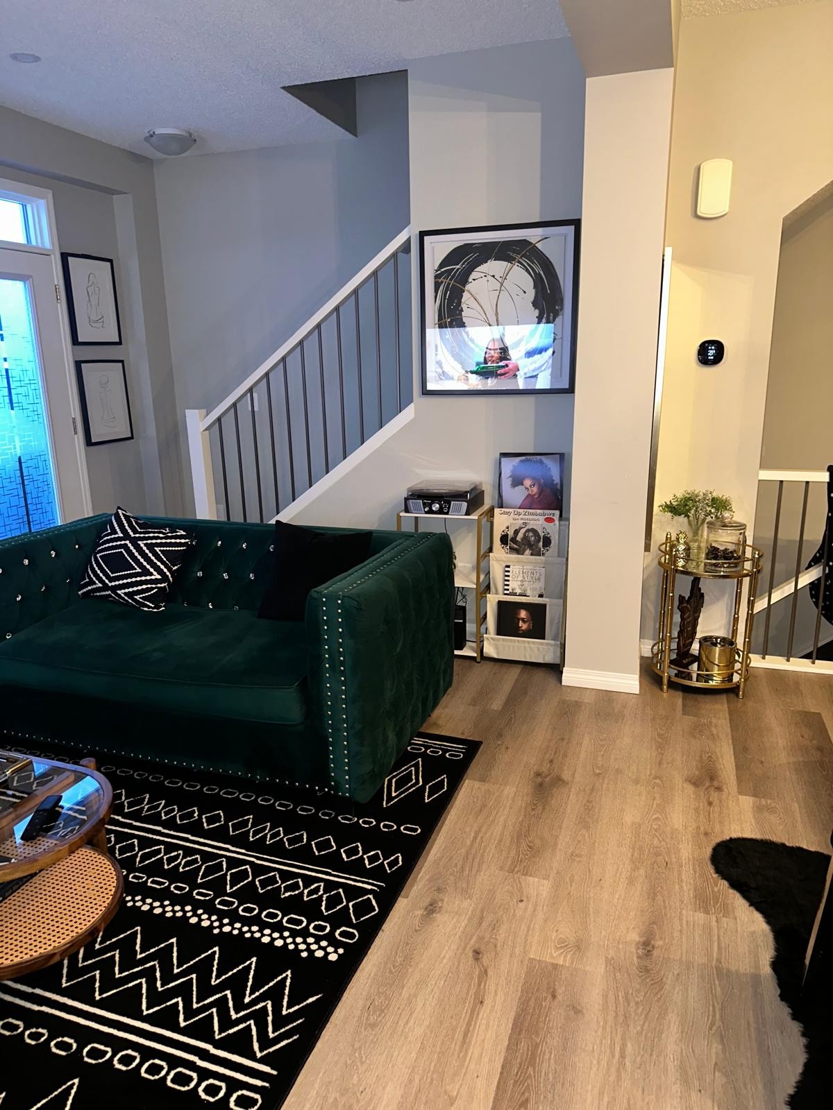 Emerald sofa beside vinyl bar and abstract circular art