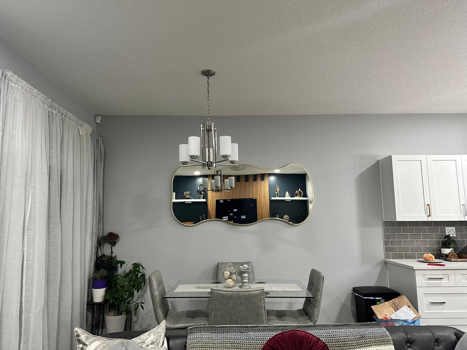 Sculptural mirror over glass dining table near the media room