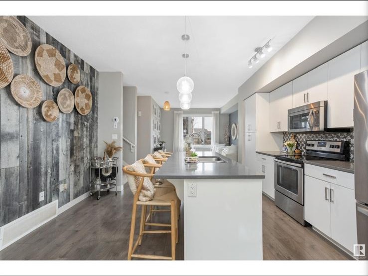 Long kitchen island with woven counter stools and pendant lights