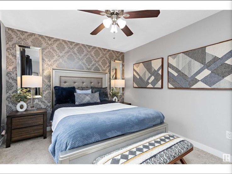Primary bedroom with damask wallpaper and tufted headboard